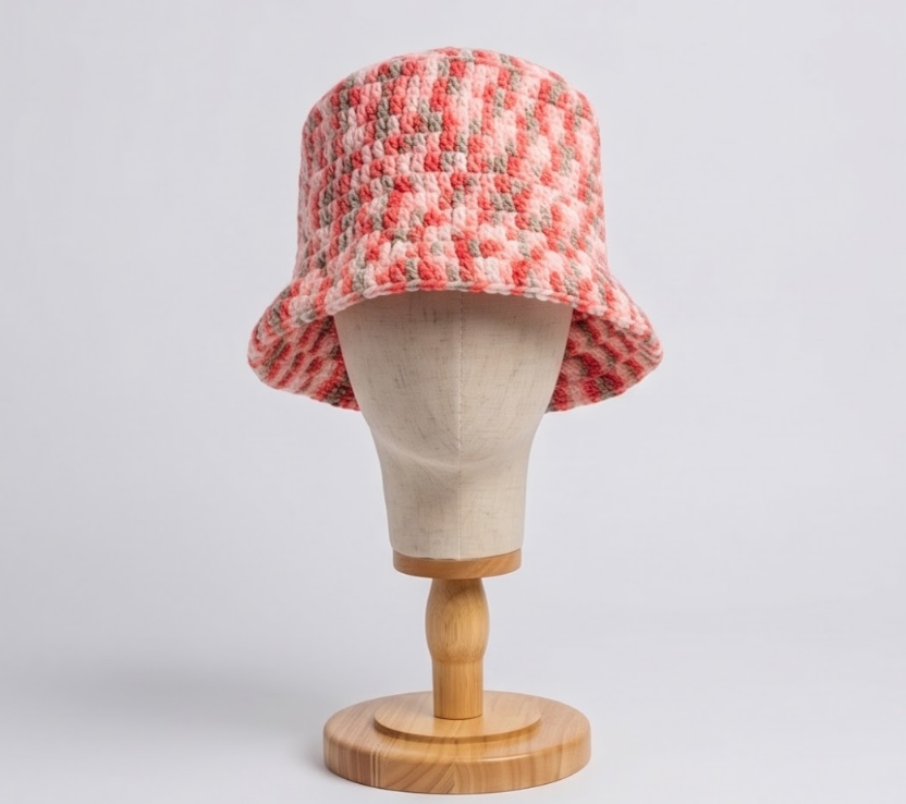 Coral-and-cream striped crochet bucket hat displayed on a wooden mannequin